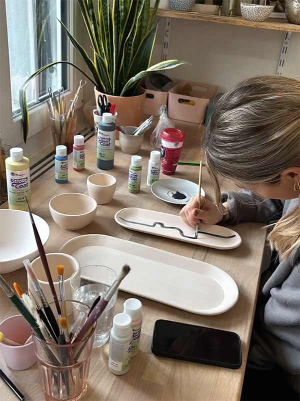 Kursteilnehmerin beim Bemalen eines vorgefertigten Keramikstücks